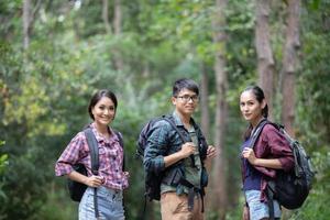 Grupo asiático de jovens caminhando com mochilas de amigos caminhando juntos e olhando o mapa e tirando a câmera fotográfica na estrada e parecendo feliz, relaxe o tempo na viagem do conceito de férias foto