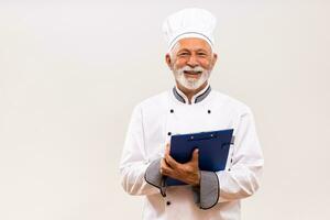 retrato do Senior chefe de cozinha segurando livro de receitas em cinzento fundo. foto