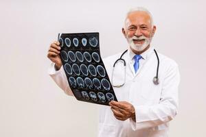 retrato do Senior médico médico segurando x raio imagem em cinzento fundo. foto