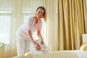 lindo hotel empregada colocando fresco e limpar \ limpo toalhas em cama dentro quarto foto
