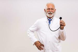 retrato do Senior médico segurando estetoscópio em cinzento fundo. foto