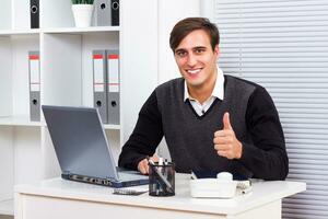 homem de negocios usando computador portátil e mostrando polegar acima foto