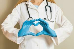 imagem do fêmea médico mostrando coração forma com mãos. foto