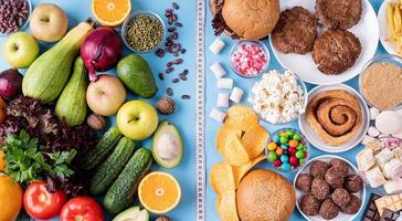 frutas e vegetais vs doces e fast food vista superior plana sobre fundo azul foto