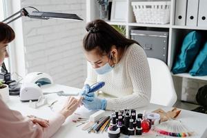 mestre de manicure usando uma máquina elétrica para remover o esmalte durante a manicure no salão foto