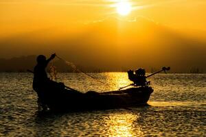 silhueta pescador e pôr do sol céu em a lago. foto