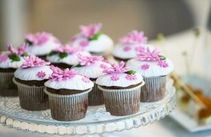 bolo para uma bufê mesa. uma grupo do pequeno bolos de copo decorado com Rosa creme flores foto