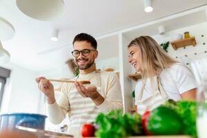 retrato de casal jovem feliz cozinhando juntos na cozinha em casa. jovem atraente romântica e homem bonito estão gostando de passar o tempo juntos enquanto estão na cozinha moderna e clara. foto