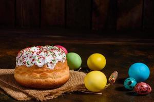 bolo de páscoa e ovos coloridos em um fundo escuro foto