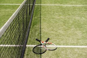 uma raquete de tênis e uma nova bola de tênis em uma quadra de tênis recém-pintada foto