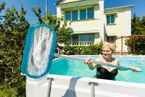 mulher limpeza a piscina às dela país casa. verão às casa conceito. estilo de vida foto