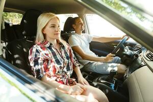 feliz jovem homem e mulher dentro uma carro desfrutando uma estrada viagem em uma verão dia. foto