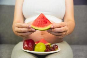 mulher grávida come fruta melancia maçã uva foto