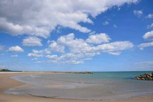 uma arenoso de praia com azul céu e nuvens foto
