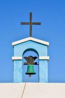 uma azul Sino e Cruz em topo do uma Igreja foto