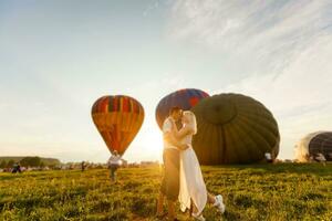 lindo romântico casal abraçando às Prado. quente ar balão em uma fundo foto
