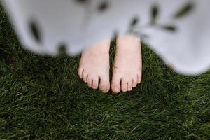 vista de cima de perto dos pés descalços da criança na grama verde, conceito de natureza foto
