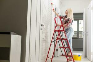 feliz mulher faz reparos dentro quarto às casa foto