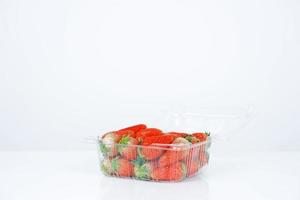 caixa de plástico com morangos no fundo branco foto