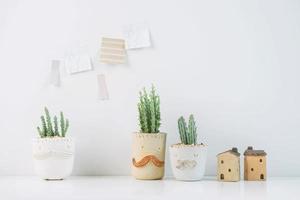 suculentas ou cactos em plantas de vasos de barro em vasos diferentes. cactos em vasos de plantas com nota adesiva na parede branca foto