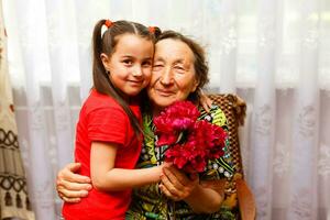 pequeno menina visitando dela eu vou avó dando flores foto