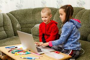 distância Aprendendo conectados Educação. escola Garoto e menina estudando às casa com computador portátil caderno e fazendo trabalho de casa. sentado às uma mesa foto