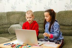 distância Aprendendo conectados Educação. escola Garoto e menina estudando às casa com computador portátil caderno e fazendo trabalho de casa. sentado às uma mesa foto