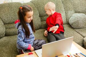 dois lindo fofa feliz sorridente crianças, uma Garoto e uma garota, usar computador portátil para distância Aprendendo ou entretenimento. foto