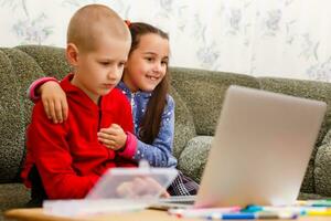 distância Aprendendo conectados Educação. escola Garoto e menina estudando às casa com computador portátil caderno e fazendo trabalho de casa. sentado às uma mesa foto