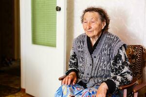 Senior mulher relaxante dentro cadeira às casa foto