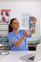 médico enfermeira segurando paciente radiografia dentro hospital escritório. radiologista dentro médico uniforme segurando e olhando às raio X, exame, osso, praticante, analisar, diagnóstico. foto