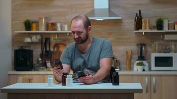 homem com dor de cabeça segurando pílulas garrafa sentado dentro a cozinha. estressado cansado infeliz preocupado pessoa sofrimento do enxaqueca, depressão, doença e ansiedade sentindo-me Exausta com tontura sintomas. foto