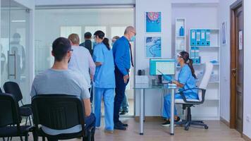 médico com viseira contra cobiçado 19 chamando paciente dentro consulta sala. Senior homem com face mascarar dentro hospital esperando quarto falando com enfermeira. Desativado mulher com zimmer quadro. foto