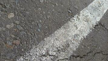 cinzento asfalto com branco linhas. rude cimento estrada superfície. rachado asfalto estrada fundo. foto