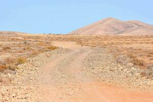 uma sujeira estrada dentro a deserto com montanhas dentro a fundo foto