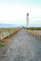 uma farol em uma sujeira estrada perto a oceano foto