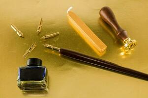 uma fonte caneta, tinta, ouro pontas, cera e uma cera foca em uma ouro frustrar superfície foto
