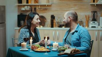 jovem homem fazer proposta para dele namorada durante romântico jantar, dentro a cozinha, sentado às a mesa bebendo uma vidro do vermelho vinho. surpreso acionado celebração noiva feliz mulher sorridente foto