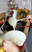 caseiro cozinha anfitriã derramando panqueca misturar a partir de concha para dentro vazando tigela foto