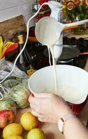 caseiro cozinha anfitriã derramando panqueca misturar a partir de concha para dentro vazando tigela foto