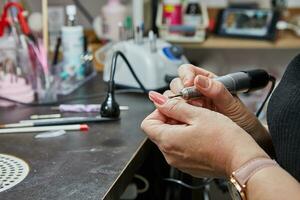 profissional unha técnico realizando gel unha extensão e manicure usando máquina foto