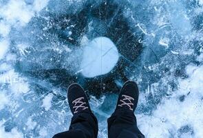 uma pé do turista em pé em a rachaduras superfície do congeladas lago baikal dentro a inverno estação do Sibéria, Rússia. foto