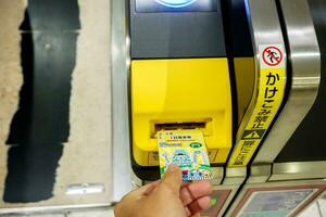 Osaka cidade, Japão, 2018 - fechar-se mão do pessoas inserir metrô bilhete dentro a Entrada automático bilhete máquinas às numba metrô estação, osaka, Japão. foto