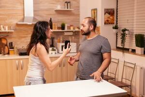 mulher olhando desapontado às marido depois de pegando ele traindo enquanto segurando telefone. aquecido Bravo frustrado ofendido irritado acusador dela homem do infidelidade mostrando ele mensagens . foto