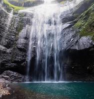Cachoeira majestosa fluindo em um penhasco rochoso na floresta tropical