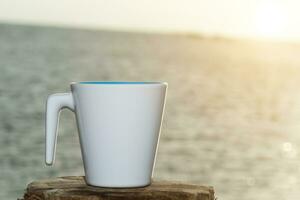 branco café caneca em a de praia. foto