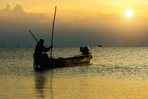 silhueta pescador e pôr do sol céu em a lago. foto