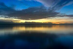 pôr do sol céu com Sombrio nuvem em a lago. foto