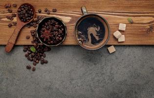 grãos de café torrados com a xícara de café configurada em fundo de pedra escura. foto