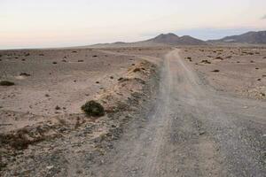 uma sujeira estrada dentro a deserto com montanhas dentro a fundo foto